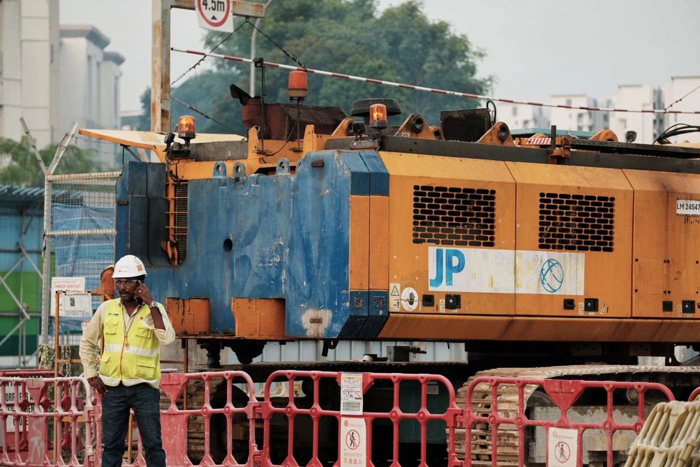 A site worker using a phone while reporting an incident from a controlled work area.