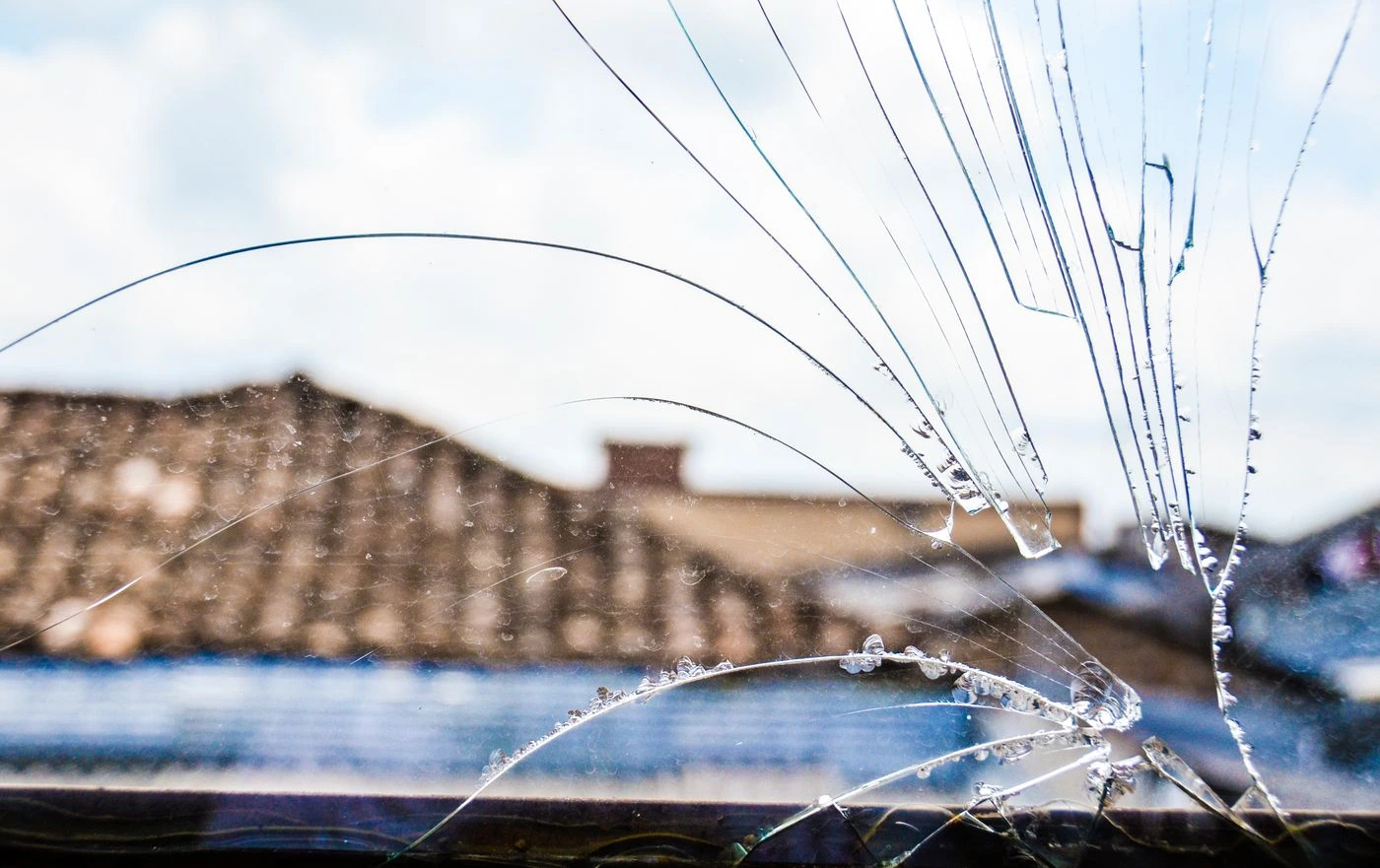 A close view of a cracked window pane with loose and fractured glass.