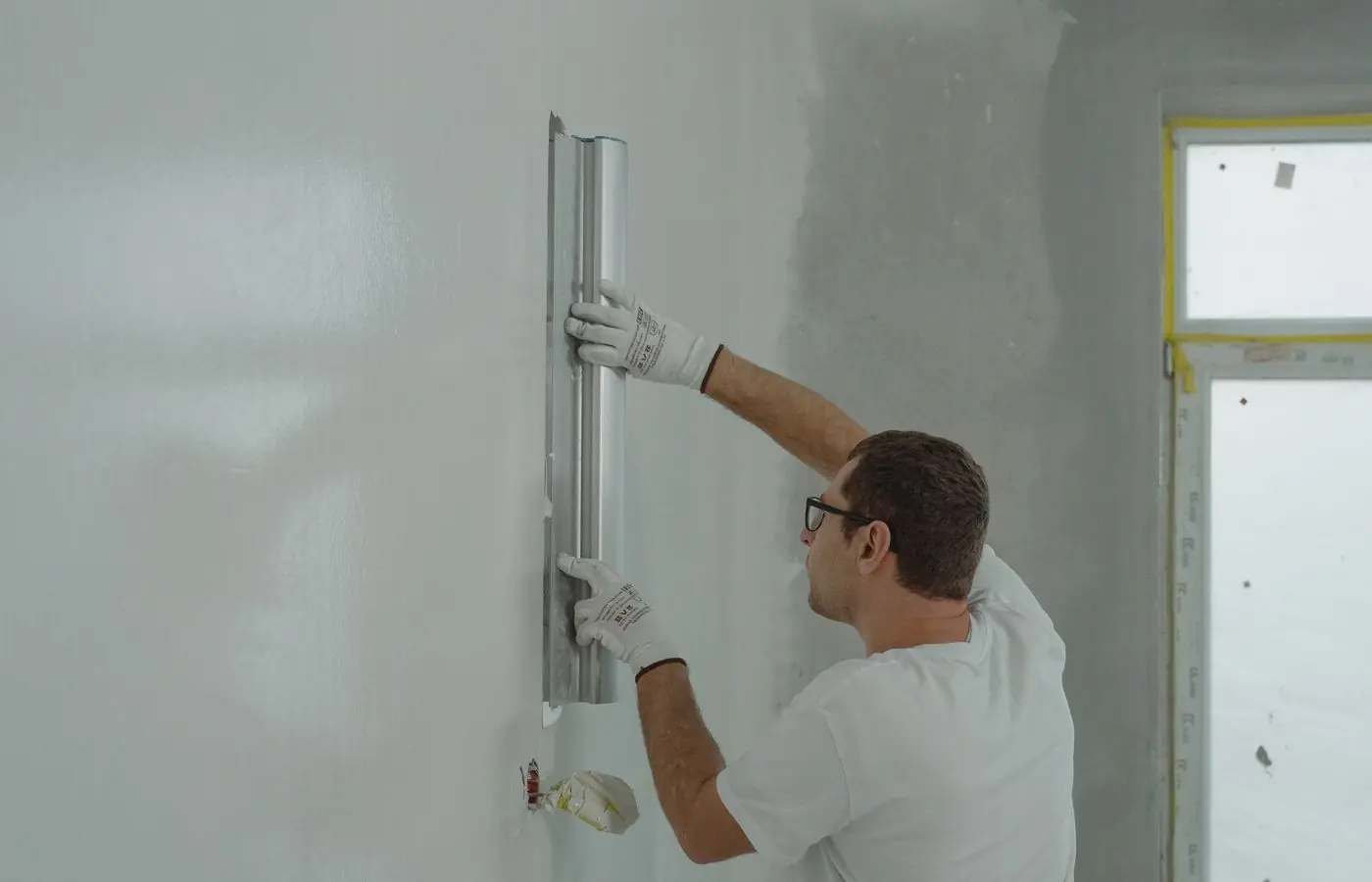 A maintenance tradesperson repairing the interior wall of a property.