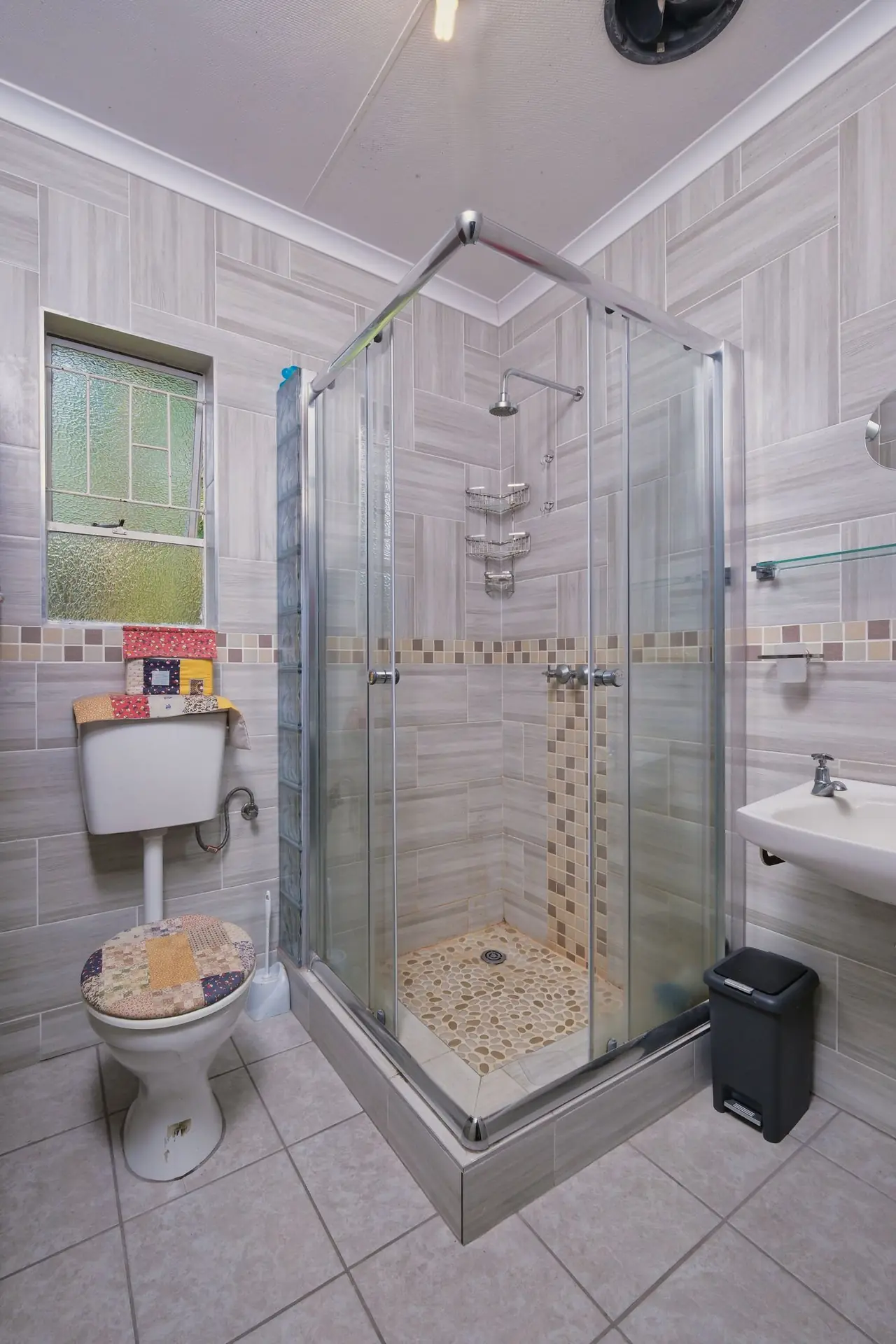 A fitted glass shower screen in a tiled residential bathroom.