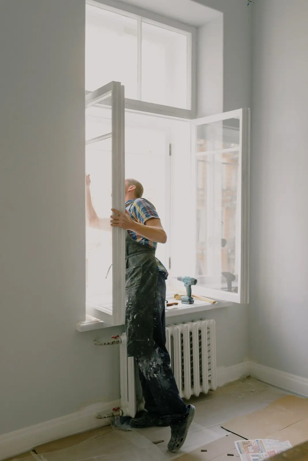 A worker checking an existing window during a glazing project.